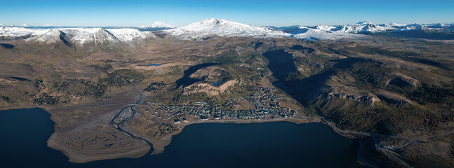 Aerial view of Caviahue town situated along the shore of lake and Copahue volcano rising in the background. Neuquen, Argentina
