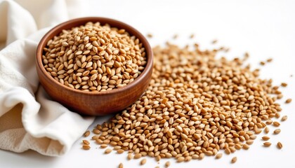 Brown sesame seeds in wooden bowl on white background with scattered seeds and cloth for healthy recipes