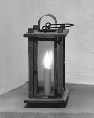 Warm light flickers softly from antique lantern illuminating the cozy corner of a rustic home at...