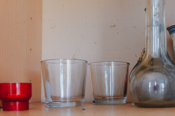 Glassware collection arranged on a rustic wooden shelf with an artistic touch and warm lighting in a cozy setting