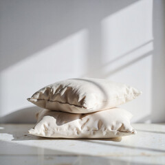Naklejka premium Soft beige pillows stacked on a surface with natural sunlight 