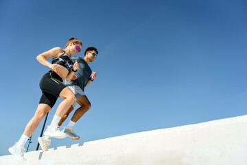 Couple jogging under a clear blue sky on a bright sunny morning for fitness and fun