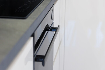 Modern black kitchen drawer handle pulls in open position against sleek white cabinetry