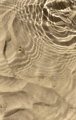 Water texture with shadows on sea beach sand