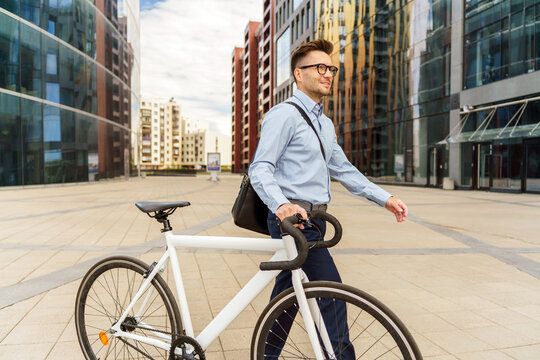 Modern man strolls through a vibrant urban landscape while walking his bicycle under a bright sky