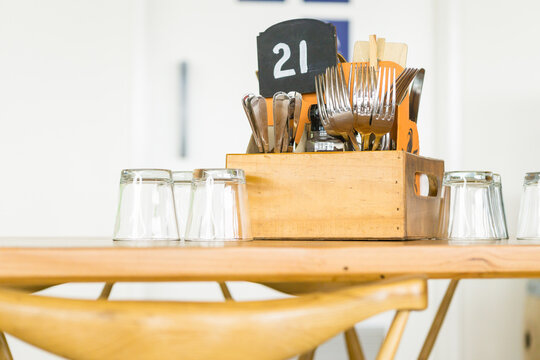 A wooden table in a restaurant with cutlery and glasses sitting on it
