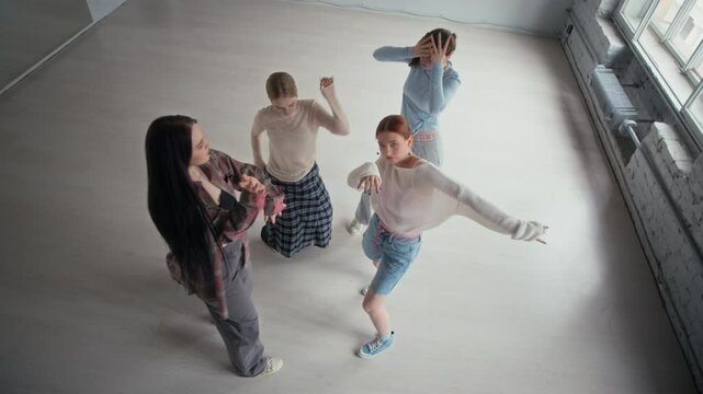 High angle shot of Caucasian female zoomers in streetwear practicing freestyle moves on camera in contemporary dance studio