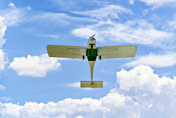 Single engine ultralight plane flying in the blue sky with white clouds	