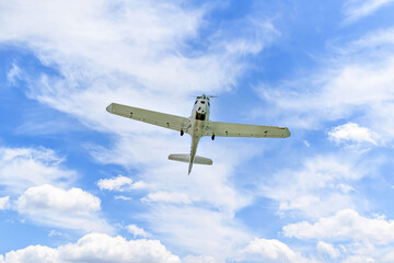 Single engine ultralight plane flying in the blue sky with white clouds	
