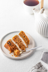 Homemade layered carrot cake with cream cheese, walnuts and spices on a plate with tea