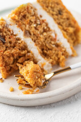 Homemade layered carrot cake with cream cheese, walnuts and spices on a plate with dessert fork close up