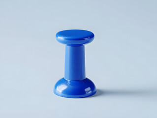 A single blue plastic pushpin or thumbtack standing upright in a minimalist composition, isolated on a light blue background.