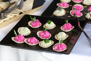 Catering buffet appetizers featuring pink and white cream cheese dips garnished with rosemary sprigs