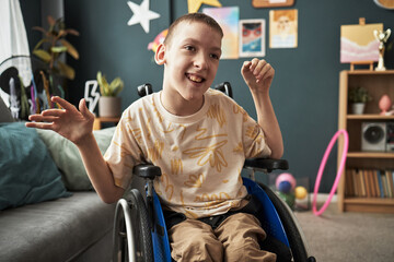 Smiling child with disability sitting in wheelchair, enjoying playful surroundings in colorful room with various toys and decorations visible © DragonImages