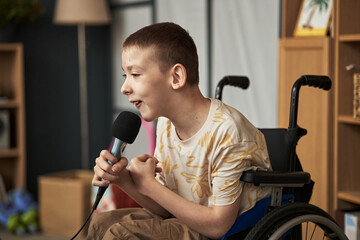 Smiling boy with disability holding microphone smiling and speaking enthusiastically in comfortable...