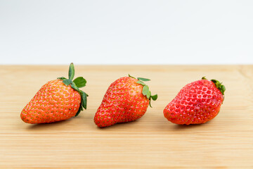 Three fresh strawberries on the cutting board