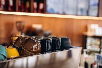 Empty cups placed on a coffee machine in a cozy cafe setting.