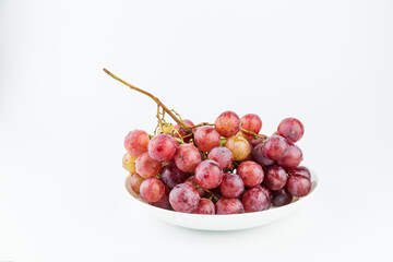 A bunch of fresh grapes and fruits on a white plate