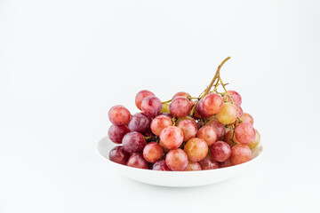 A bunch of fresh grapes and fruits on a white plate