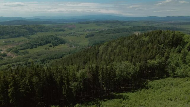Aerial view of dense green forest and open terrain spreading across hills and valleys around Chełmiec mountain near Bogusz&oacute;w-Gorce in Lower Silesia