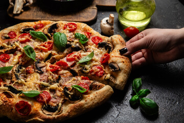 Appetizing pizza with ham, tomatoes and cheese close-up. Thin pizza