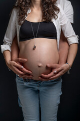 Close-up view of a man hugging a pregnant woman with her belly exposed from behind
