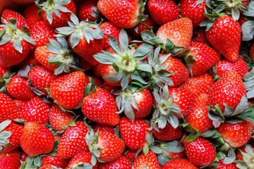 Fresh, ripe strawberries with vibrant red color and green leaves, closely packed together. Perfect...