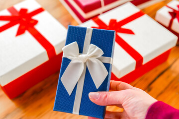 Mothers Day, Birthday, Christmas gifts and surprises. Hand Holding Blue Gift Box with...