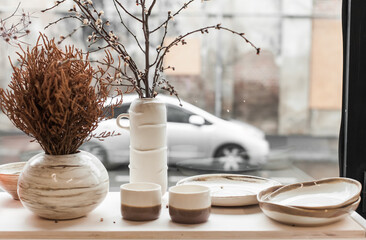 Minimalist still life of handmade ceramic decor in earthy tones. Unique pottery pieces for interior styling: vases, lamps, mirror frames, and home accessories with natural textures