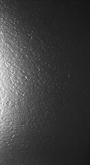 Dark gray textured surface with subtle variations in light and shadow. Abstract background showcasing a natural stone or metal material.