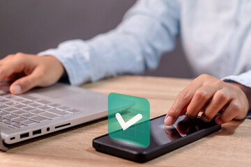A business woman using smartphone with green check mark on screen. Validated, confirmed, completed, approved , and verified concept. © fadfebrian