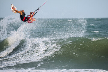 Obraz premium Man kitesurfing on ocean waves at tropical beach