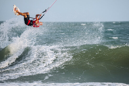 Man kitesurfing on ocean waves at tropical beach