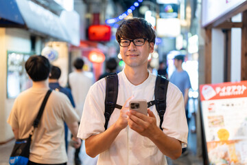 スマホを持って街を歩く男性