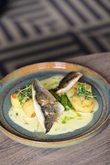 Sea Bream Fillet with Béarnaise Sauce, Herbs, and Potatoes Served on Wooden Table