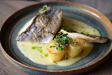 Sea Bream Fillet with Béarnaise Sauce, Herbs, and Potatoes Served on Wooden Table