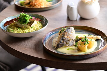 Background View of Sea Bream Dish with Hollandaise Sauce, Potatoes, and Fresh Herbs in Restaurant
