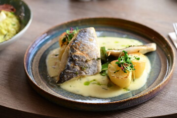 Sea Bream Fillet with Béarnaise Sauce, Herbs, and Potatoes Served on Wooden Table