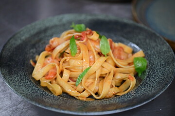 Fresh Pasta with Shrimps, Cherry Tomatoes, and Basil Served in a Restaurant