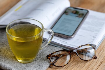 A tranquil scene featuring a cup of green tea, reading glasses, and an open book spread on a rustic wooden table, symbolizing relaxation and the joy of reading.