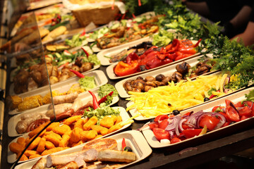 Food fair, food court. Display case with finished products. Nugents, French fries, peppers, mushrooms, salads and much more. Sale of various products at the fair. Street food to go, festival