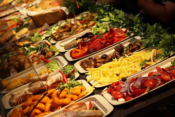 Food fair, food court. Display case with finished products. Nugents, French fries, peppers, mushrooms, salads and much more. Sale of various products at the fair. Street food to go, festival