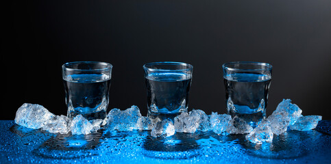 Vodka and crushed ice on a black table.