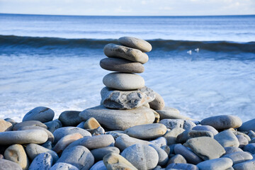 Cairn of  smooth stones placed at the oceans edge on the beach in Wales, a lovely peaceful display with waves lapping gently towards them.