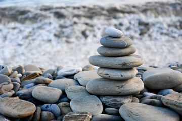 Close up shot of a pile of smooth stones formed into a cairn  on beach by the ocean in Wales UK 
