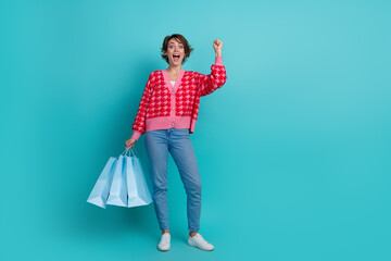 Full length photo of positive lucky lady wear pink cardigan holding shoppers emtpy space isolated teal color background