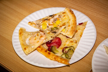 three pieces of different pizza, lying on a disposable white plate, many ingredients, sausage, chicken, mushrooms, cheese, thin dough, fresh, appetizing, snack, appetizer, lunch, made to order