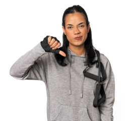 Young Filipina athlete with resistance bands showing a dislike gesture, thumbs down. Disagreement concept.
