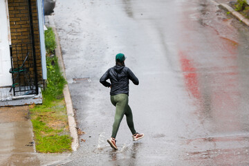 Une femme court sous la pluie en ville.