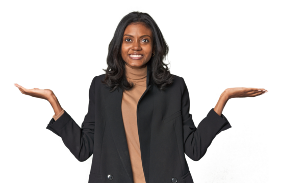Young Indian woman in business suit makes scale with arms, feels happy and confident. - Powered by Adobe